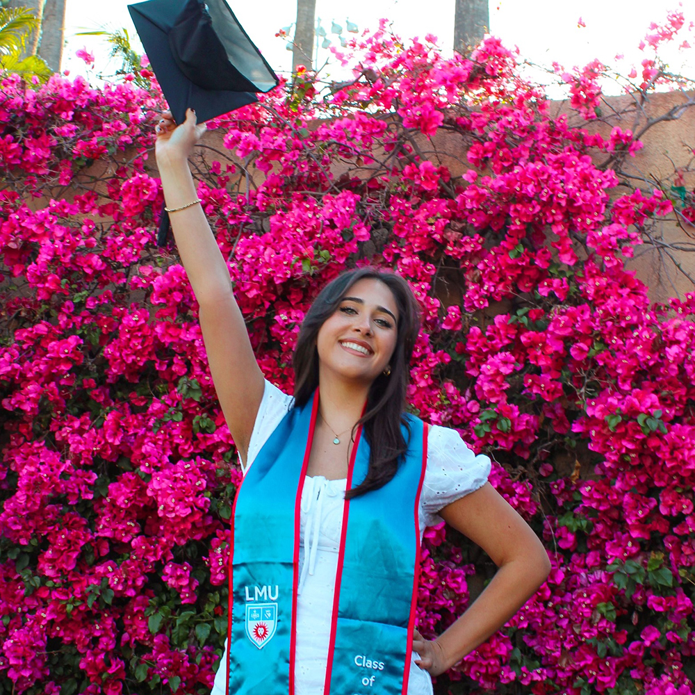 A young woman graduate in front of flowers